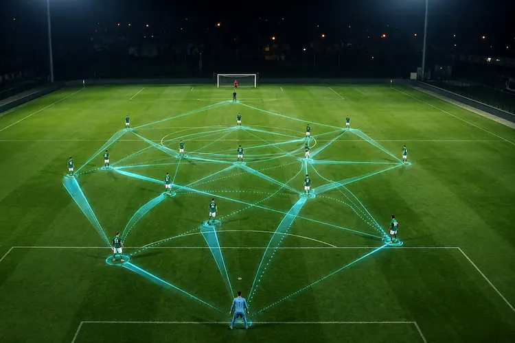 Jogadores em campo conectados por linhas digitais azuis que representam grafos e análise tática por inteligência artificial no futebol.